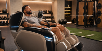 Professional athlete relaxing in an Ogawa massage chair in a modern gym recovery space.