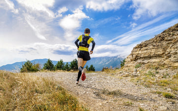 man running on trail with full equipment during daytime
